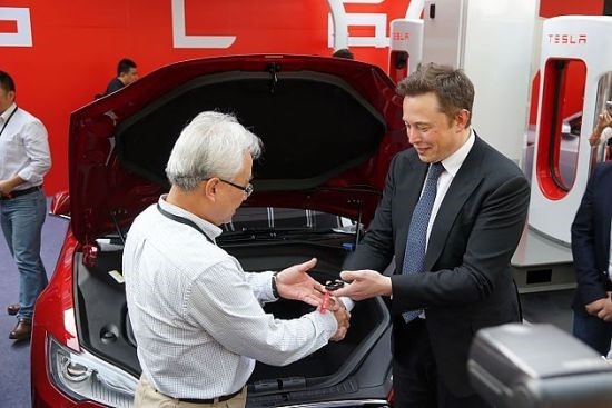 사진=2014년 상하이에서 처음으로 판매되는 모델S 자동차키를 넘겨주는 일론 머스크(바이두)